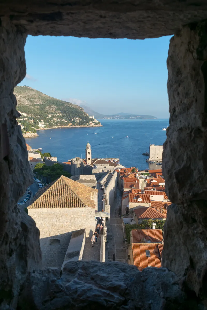 Terracotta rooftops and the sea viewed through a stone gap in the city walls, Dubrovnik, Croatia