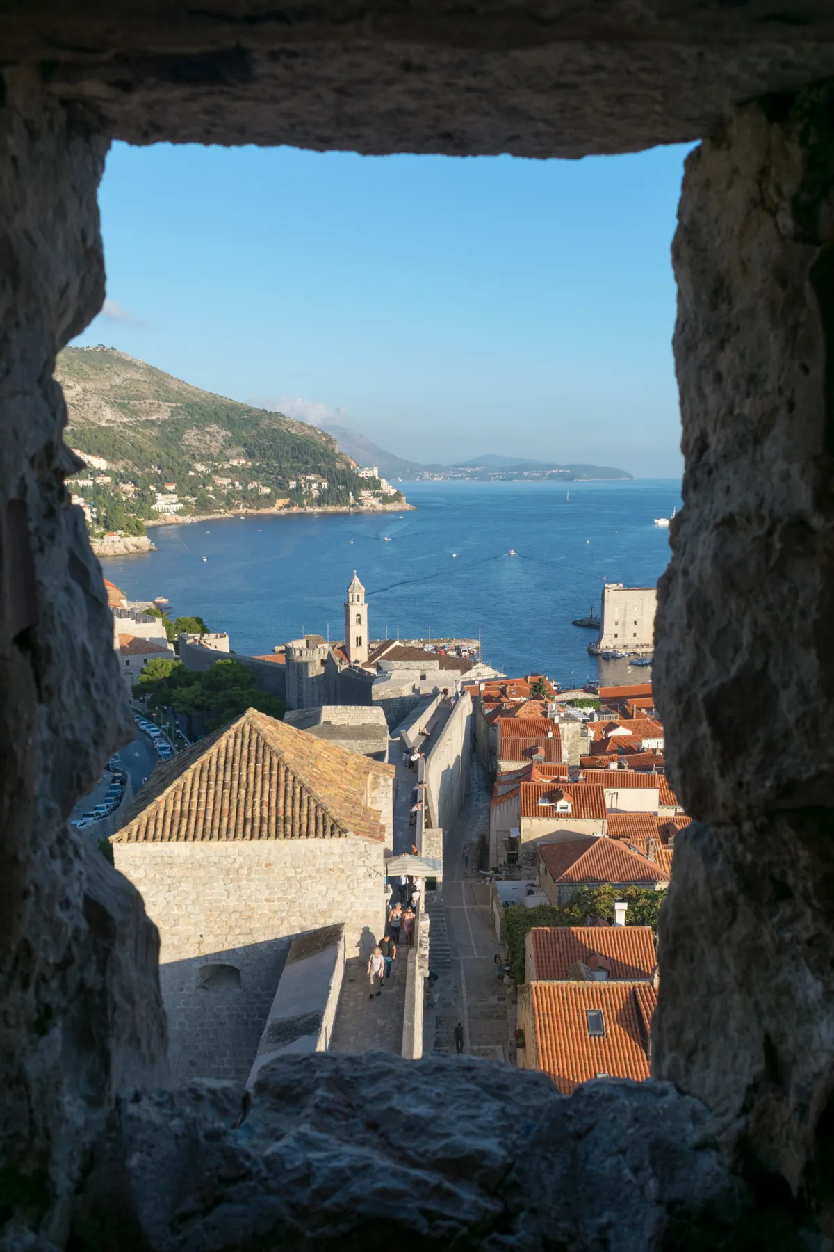Terracotta rooftops and the sea viewed through a stone gap in the city walls, Dubrovnik, Croatia