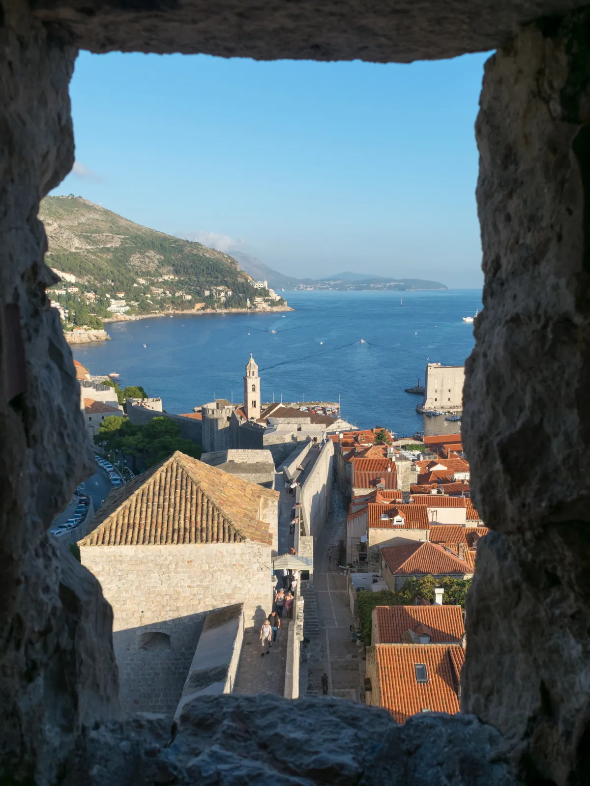 Terracotta rooftops and the sea viewed through a stone gap in the city walls, Dubrovnik, Croatia