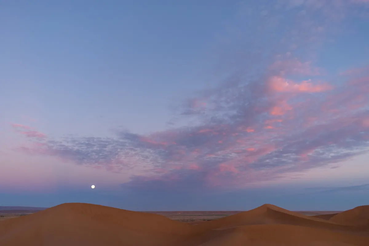 Full moon rising over Sahara sand dunes under a pink and violet dusk sky, M'Hamid, Morocco
